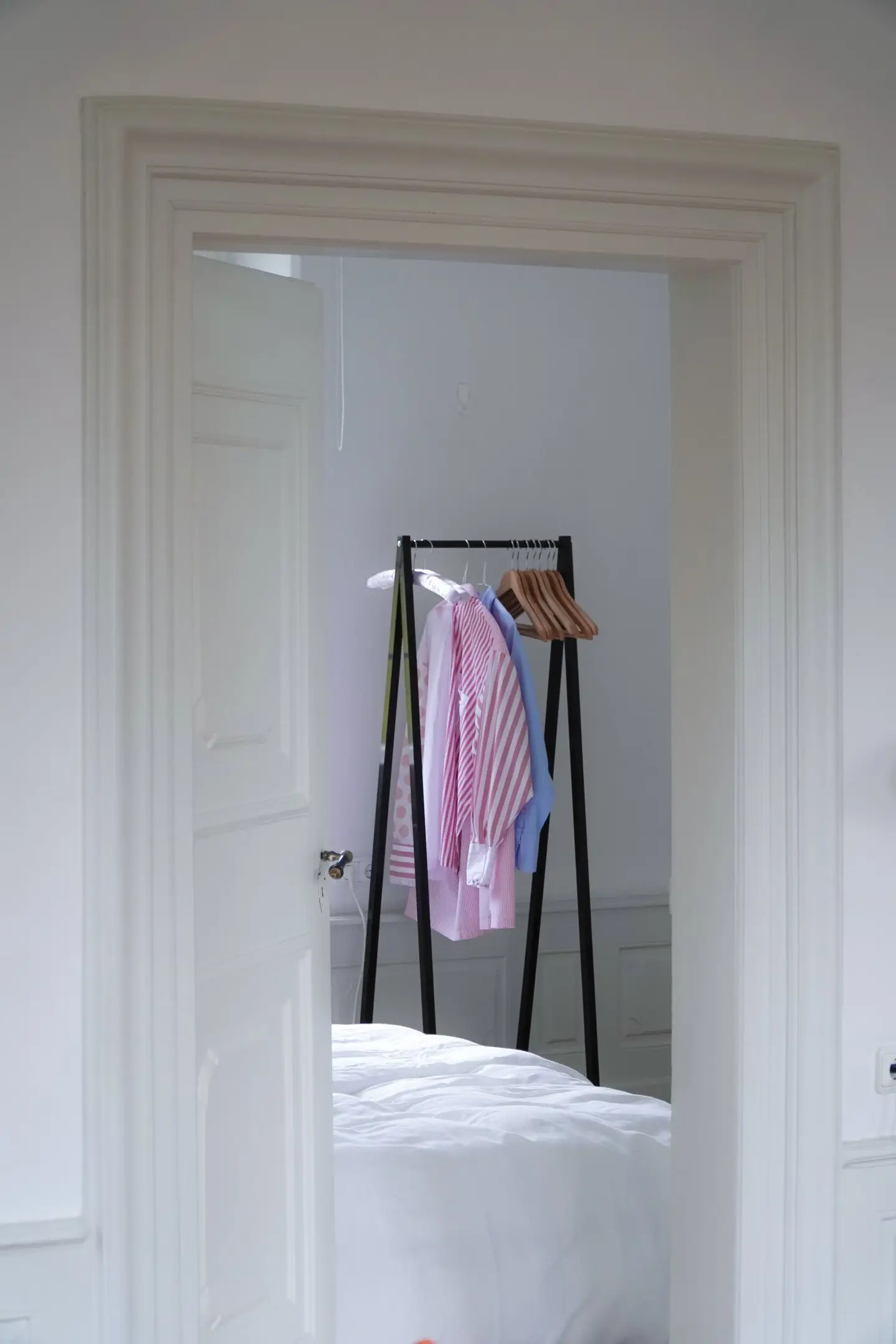 Blick durch eine Tür auf Kleiderständer und Bett