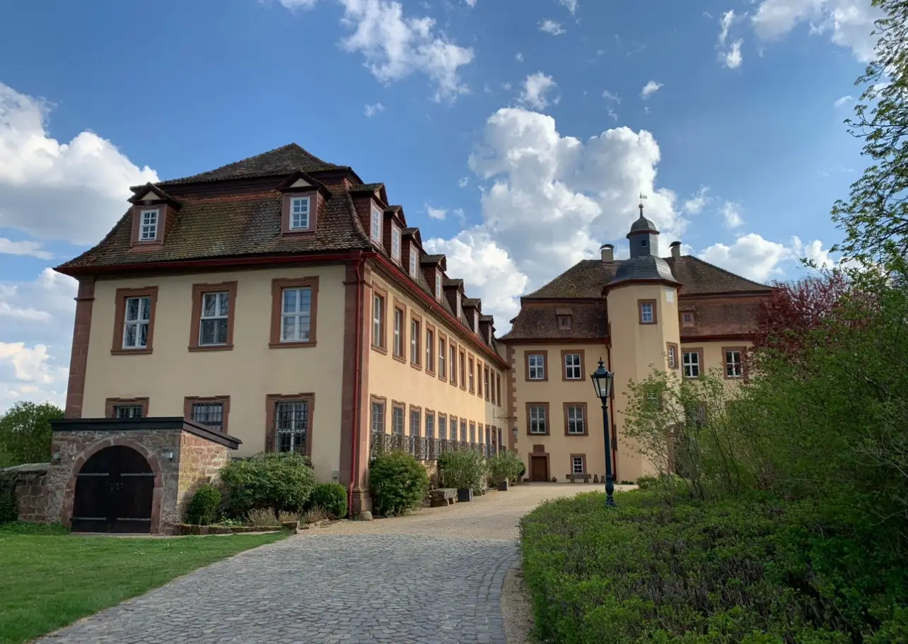 Kiesweg zur Schlossfassade mit Turm unter blauem Himmel