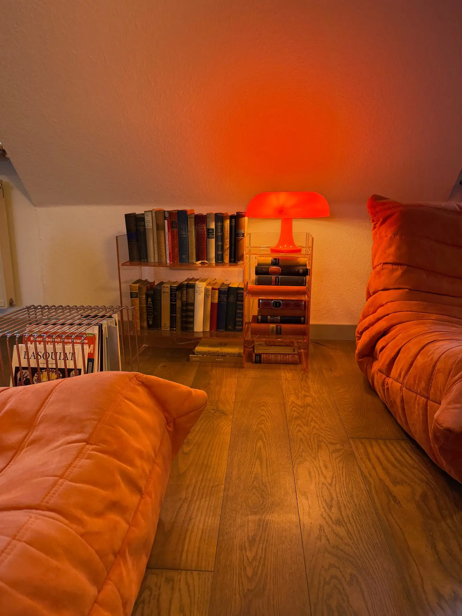 Leseecke mit Bücherregal, orangefarbener Lampe und Sofa