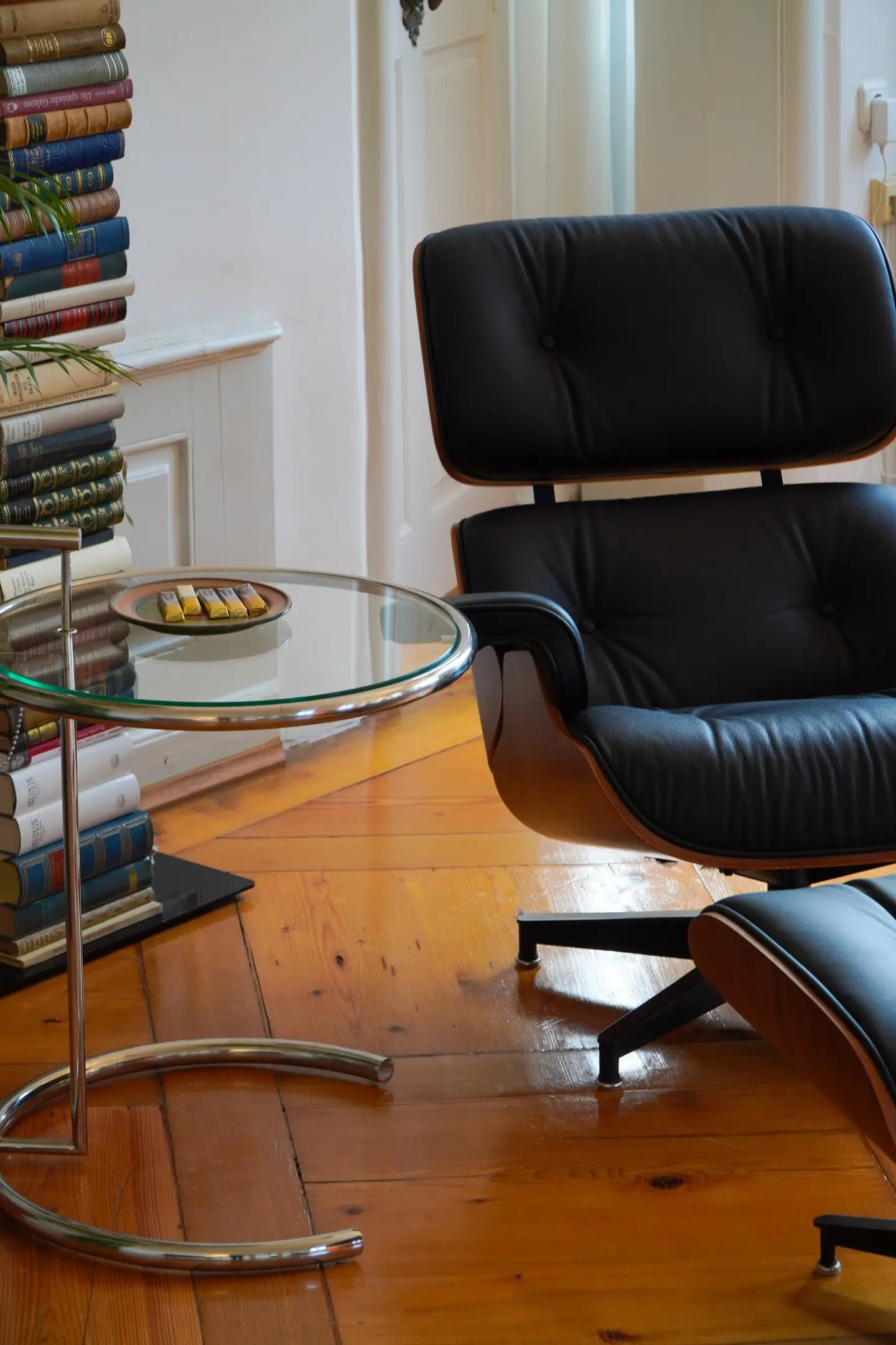 Schwarzer Loungesessel neben einem Glastisch und Bücherstapeln