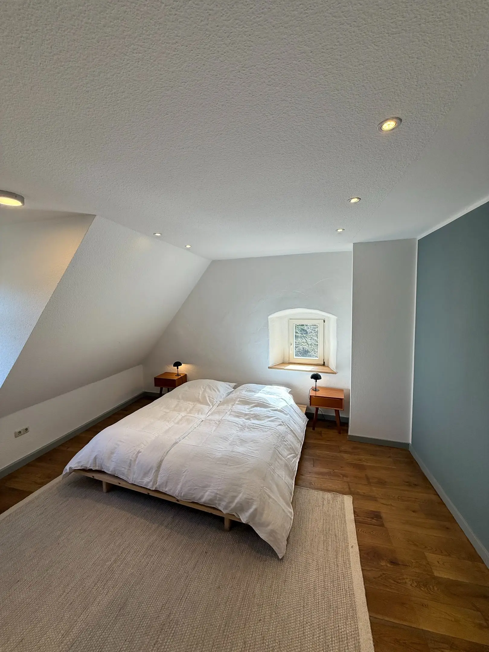 Schlafzimmer unter dem Dach mit großem Bett und Teppich