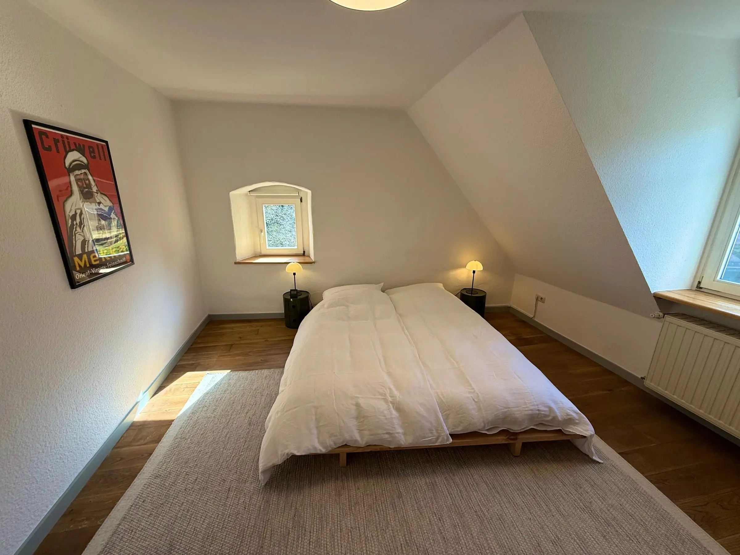 Dachschlafzimmer mit Doppelbett und kleinem Fenster