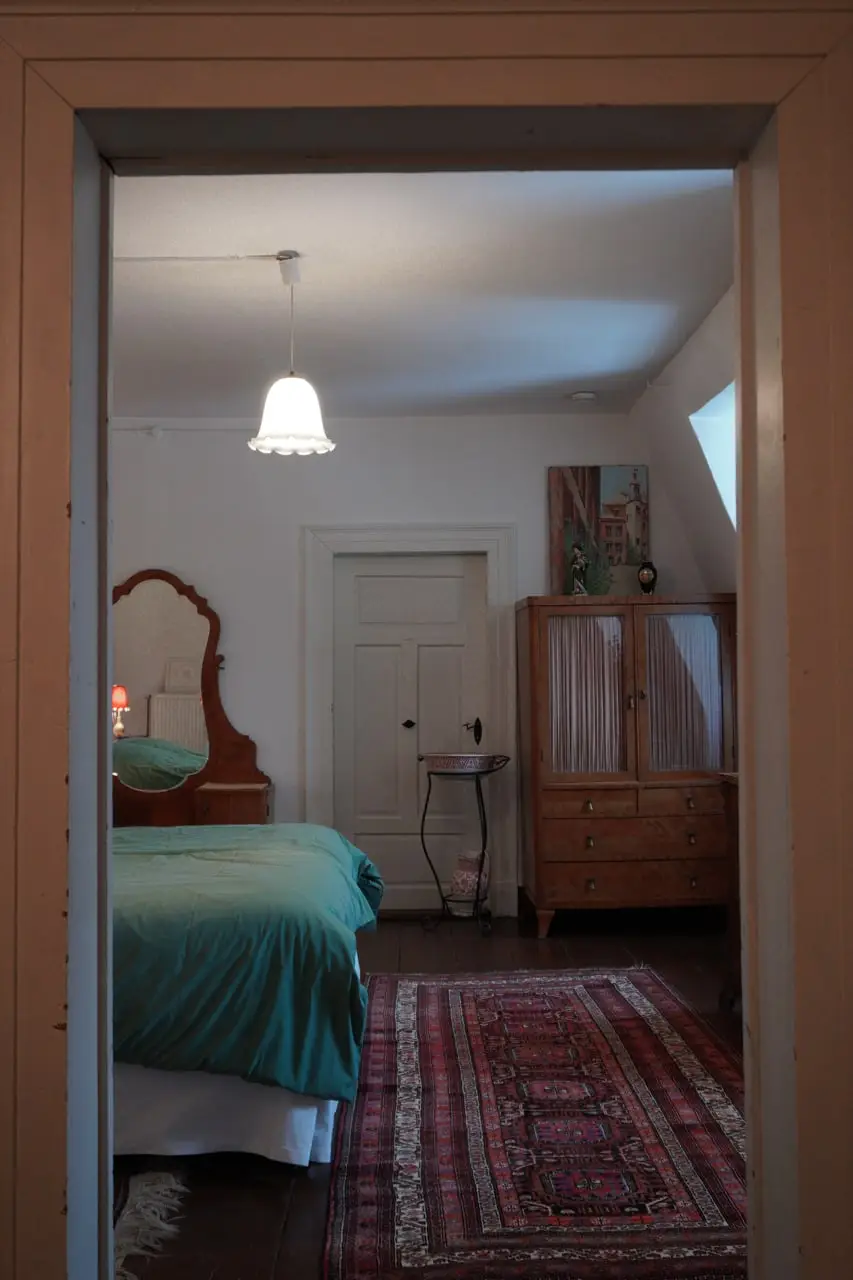 Blick durch die Tür ins Schlafzimmer mit Holzschrank und Orientteppich