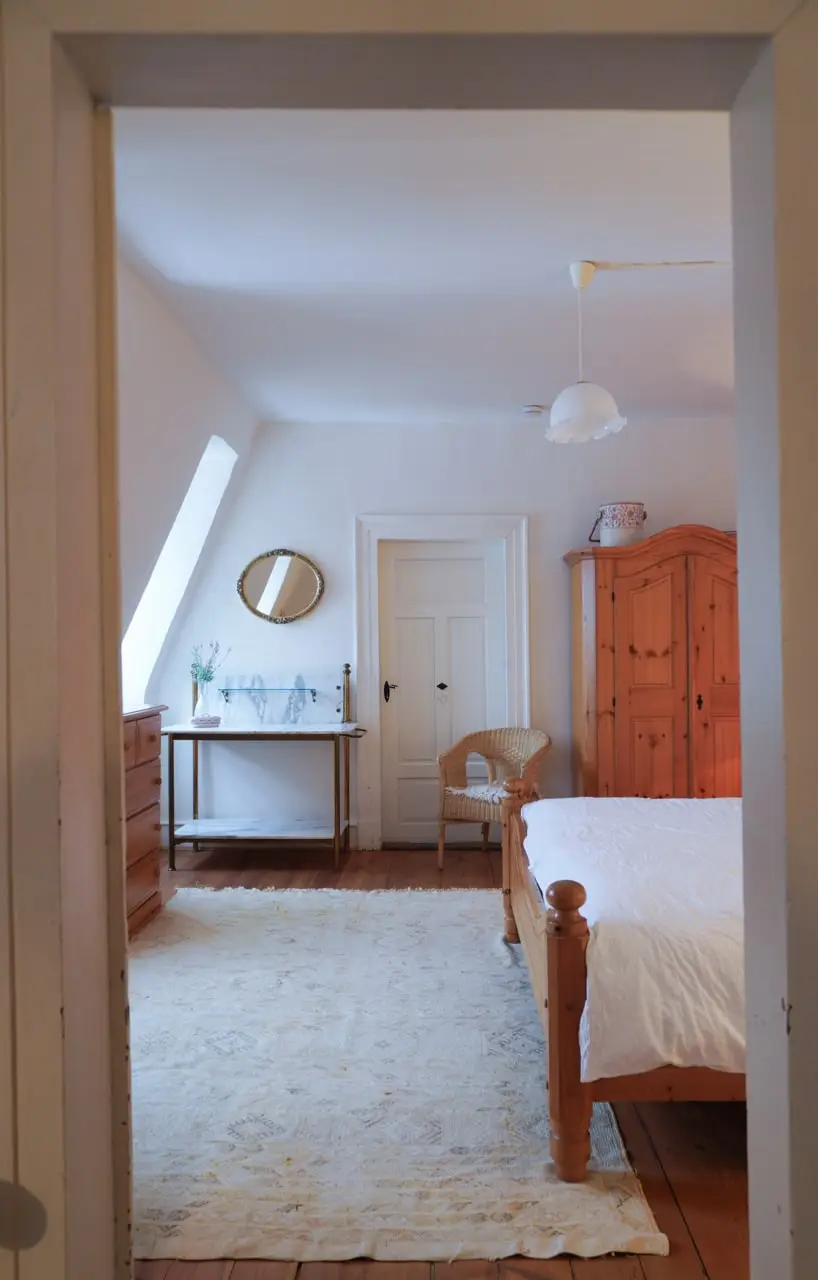 Helles Dachschlafzimmer mit Bett, Waschtisch und Holzschrank