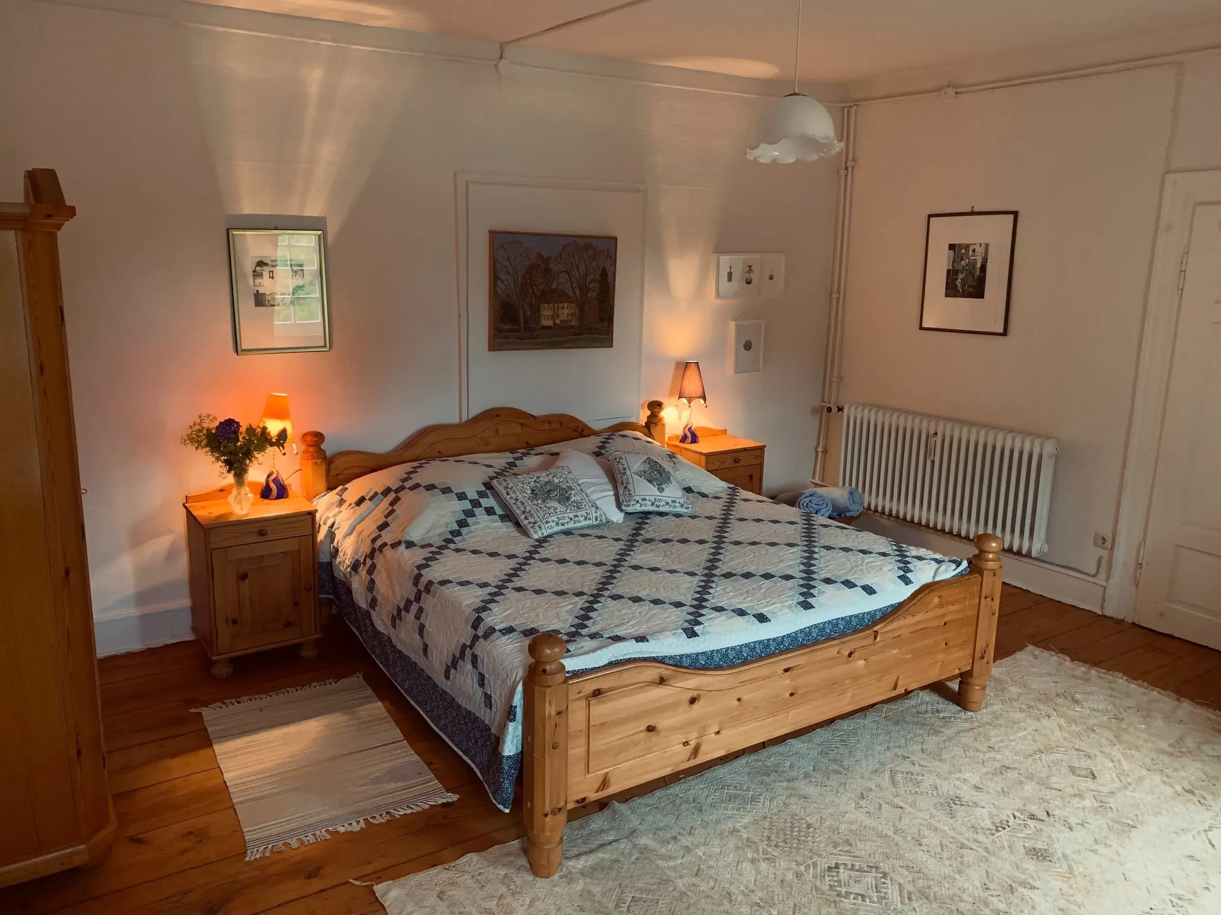 Schlafzimmer mit Holzbett und gemusterter Tagesdecke unter der Dachschräge