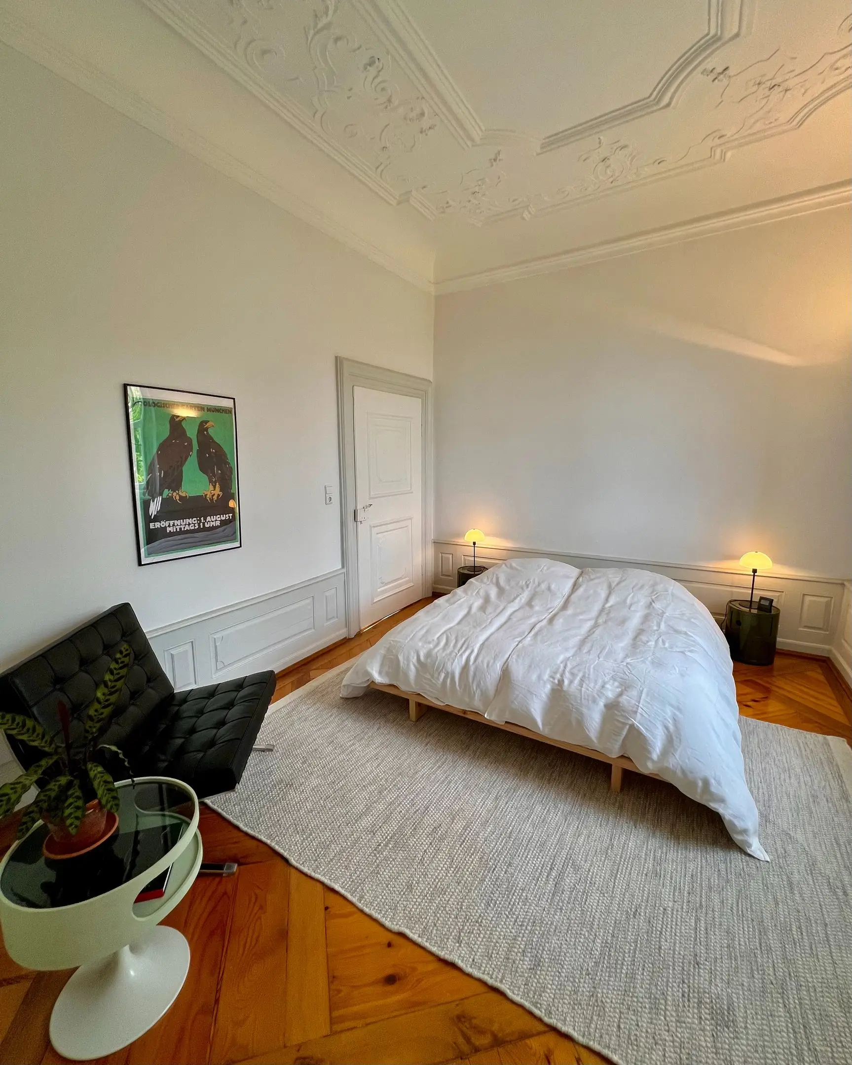 Schlafzimmer mit Stuckdecke, Doppelbett und Ledersessel
