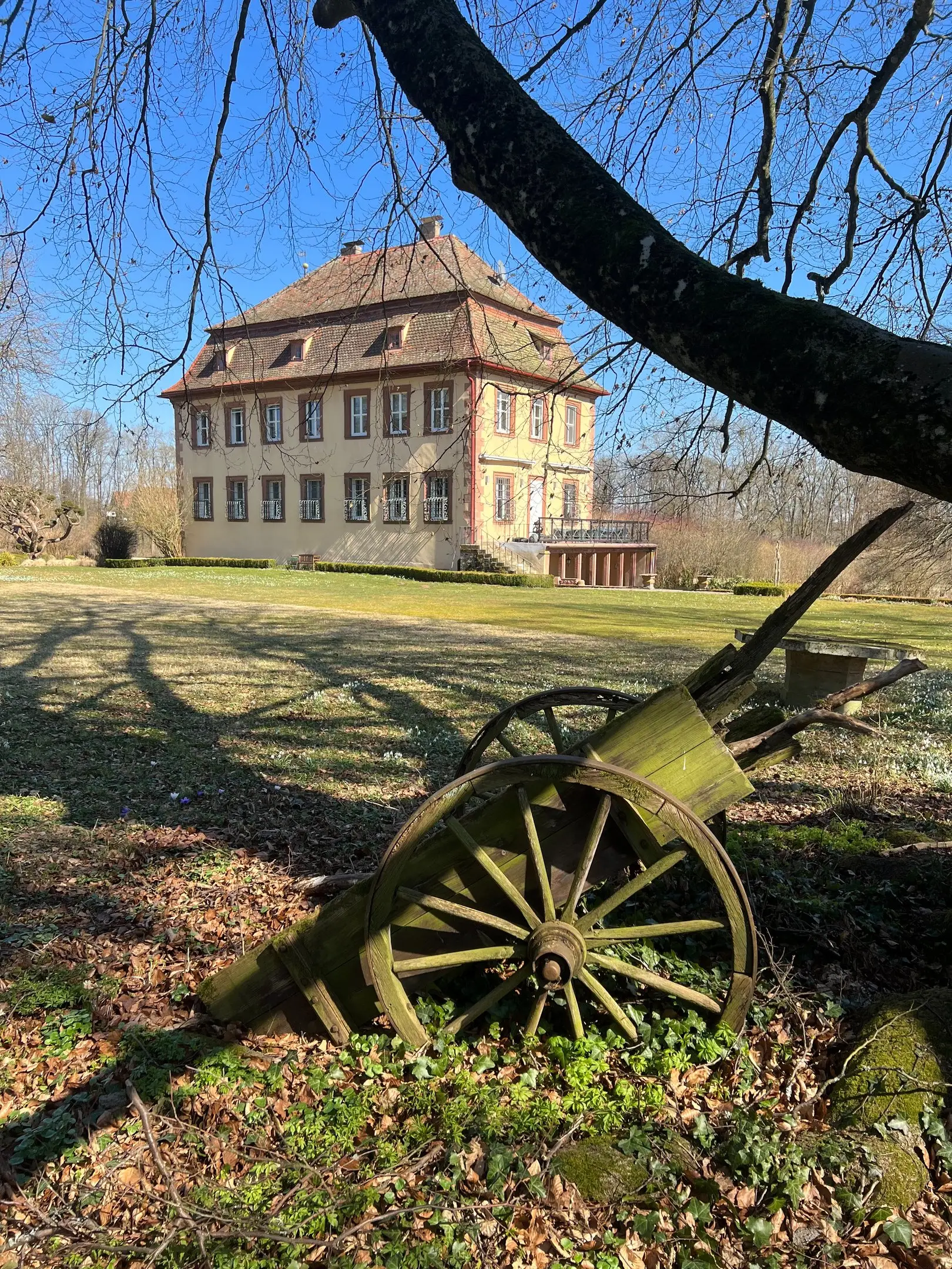 Historischer Holzwagen im Park, im Hintergrund das Schloss
