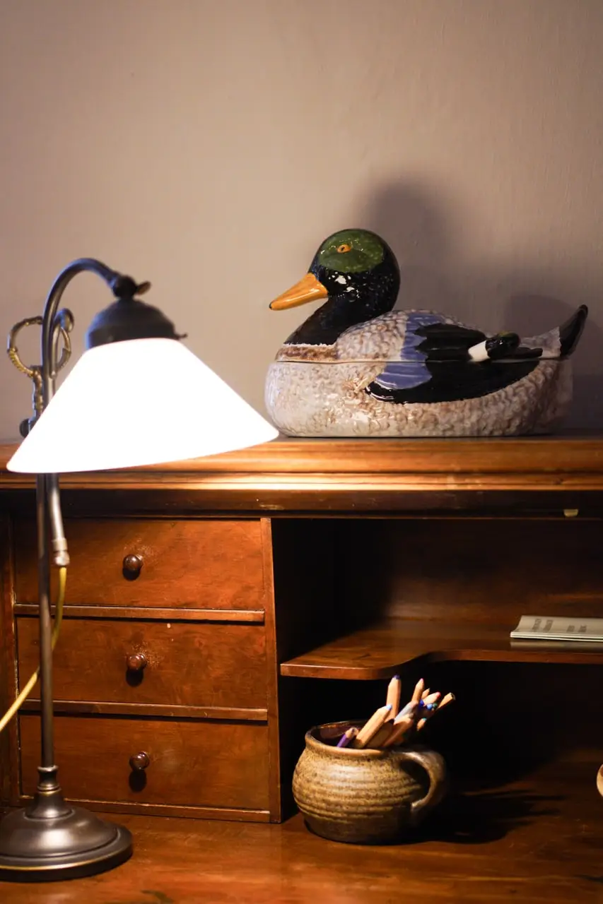 Schreibtischlampe und Holzente auf dem Sekretär