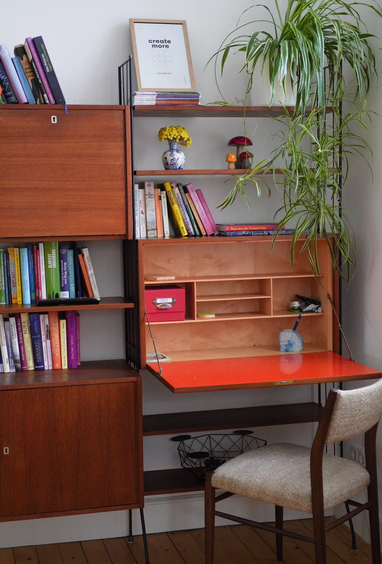 Wandregal mit Büchern und aufgeklapptem Sekretär