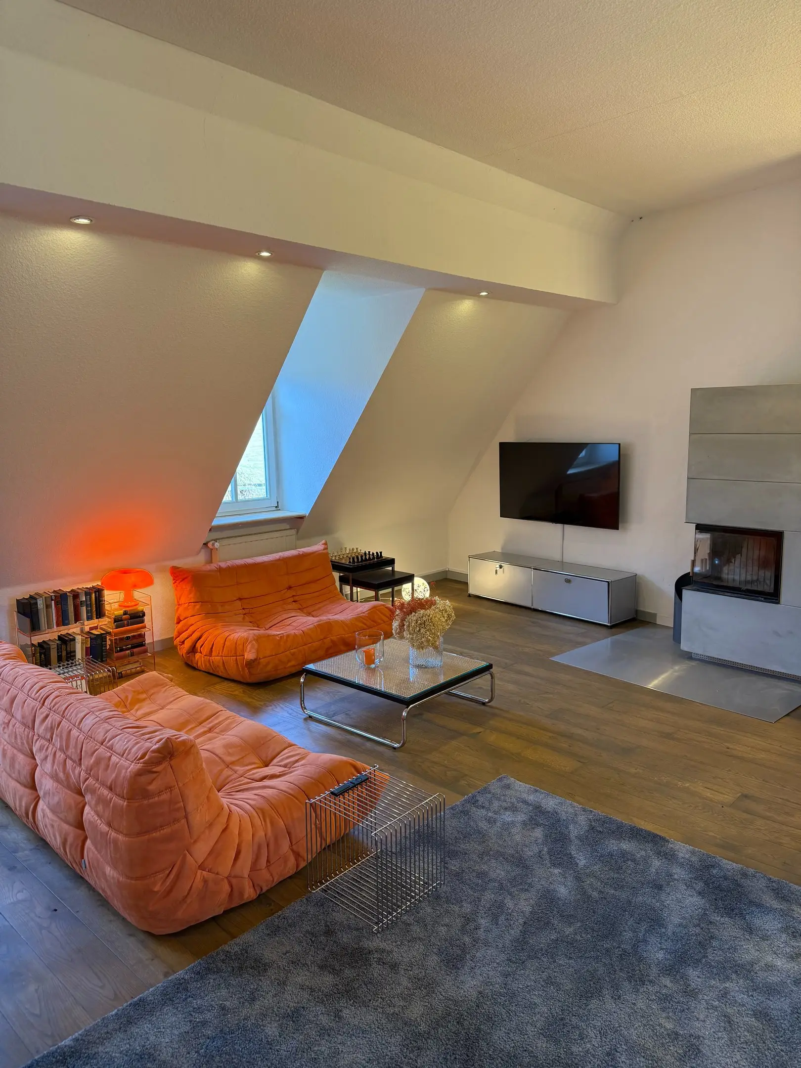 Wohnzimmer mit orangefarbenen Sofas, Kamin und Fernseher