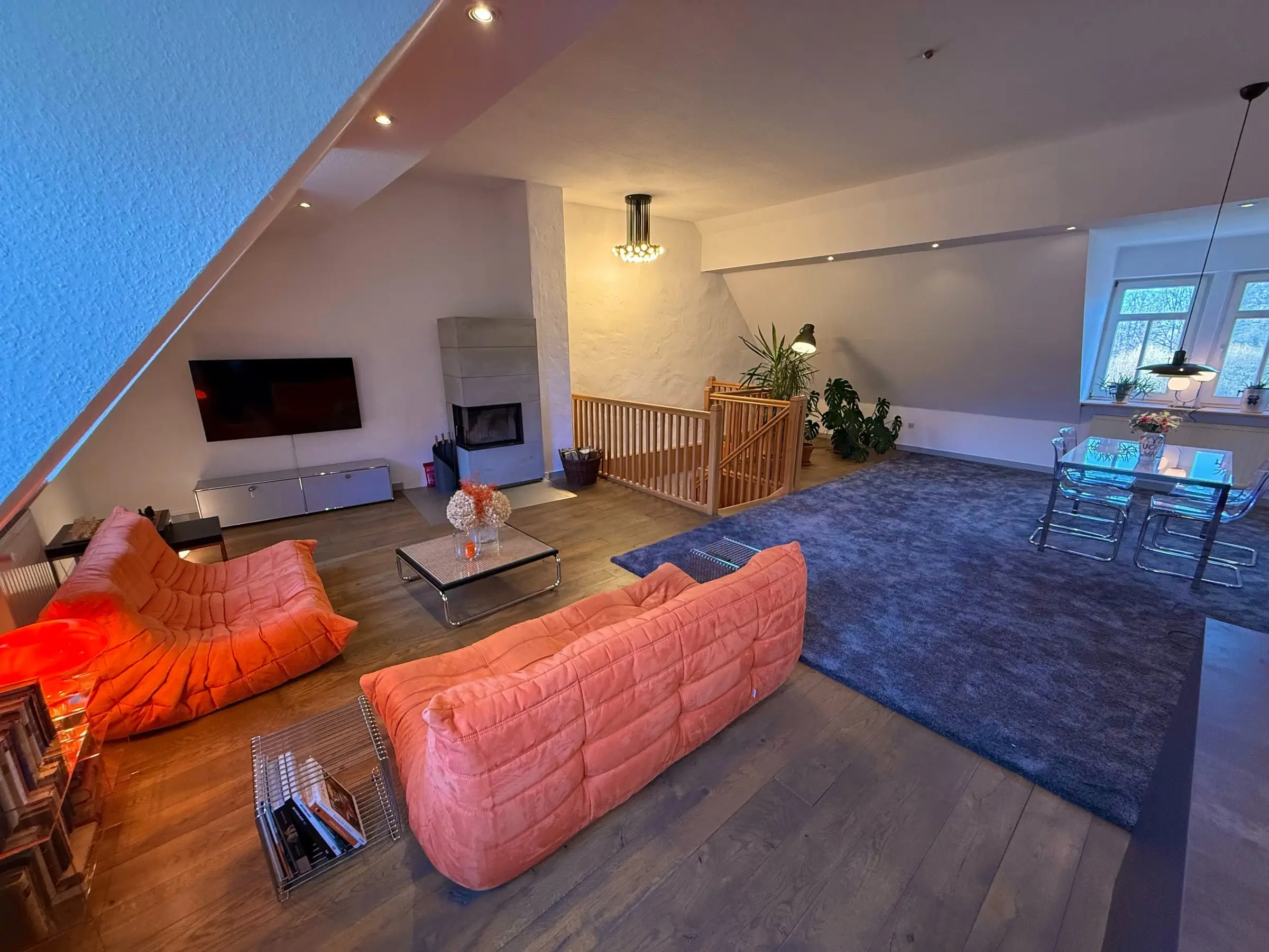 Offener Wohnbereich unter dem Dach mit orangefarbenen Sofas